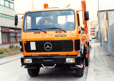 Orangefarbener HAAF Containerdienst Mercedes-LKW in Frontansicht auf einer Straße.