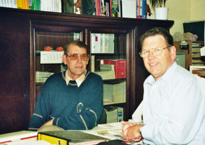 Robert Haaf und Roland Haaf sitzen im Büro an einem Schreibtisch mit Unterlagen und Ordnern.