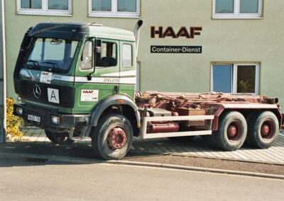 Grüner LKW mit Fahrgestell steht vor dem HAAF Firmengebäude.