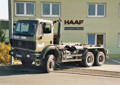 Olivfarbener LKW ohne Aufbau steht vor dem HAAF Firmengebäude.