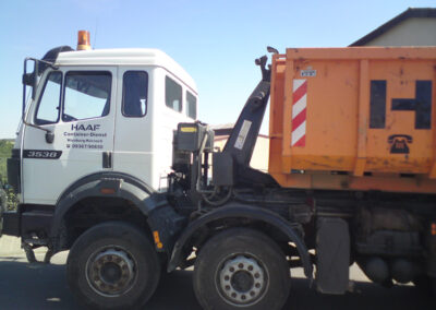 Weißer HAAF-LKW mit orangefarbenem Container und Ladekran in Seitenansicht.