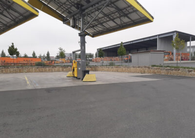 Überdachte LKW-Waage bzw. Umschlagstation auf einem asphaltierten Betriebshof mit Hallen im Hintergrund.