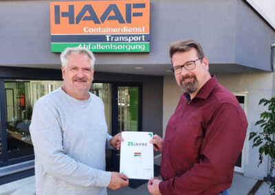 Alexander Haaf und Markus Haaf stehen vor dem Eingang des HAAF Containerdienstes und halten gemeinsam ein Zertifikat in der Hand.