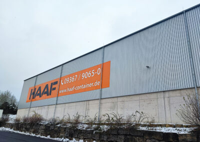 Große Hallenfassade mit HAAF-Logo und orangefarbener Beschriftung „Containerdienst Transport Entsorgung“ in Kürnach.