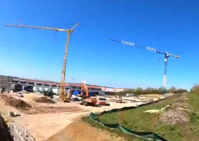 Weitläufige Baustelle mit Kränen, Erdbewegungen und vorbereiteten Flächen für Hallen am Wachtelberg 14.