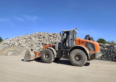 Großer Radlader fährt auf dem Gelände des RecyclingCenter Bergtheim vor einem Haufen aus gebrochenem Bauschutt.