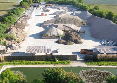 Luftaufnahme des RecyclingCenter Bergtheim mit großen Haufen von Bauschutt, Schotter und Erdmaterialien sowie Fahrwegen.